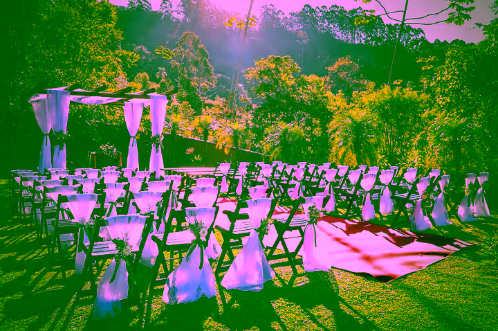 Cerimônia de casamento montada no gramado, com cadeiras e tendas brancas e a serra ao fundo
